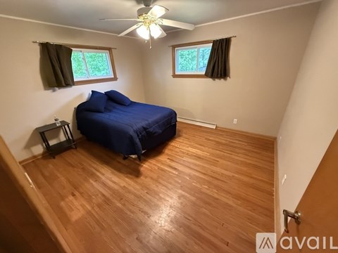 A bedroom with a blue bed and wooden floors.