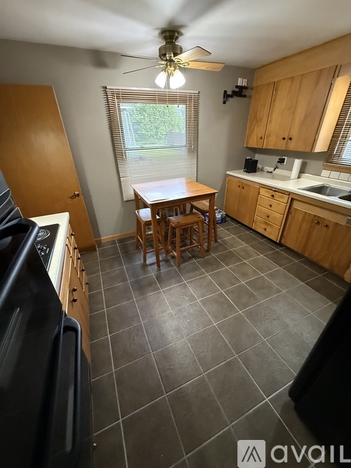 A kitchen with a black fridge and wooden cabinets.