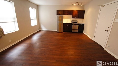 A kitchen with dark wood floors and white walls.