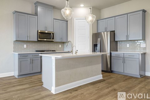 A kitchen with a white island in the middle and a refrigerator to the right.