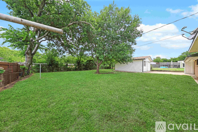 A backyard with a green lawn and trees.