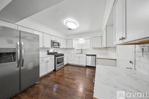 A kitchen with white cabinets and a stainless steel refrigerator.