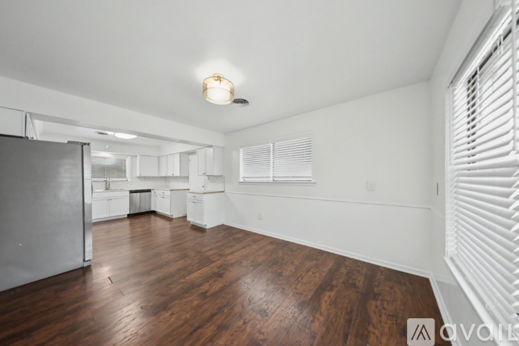 A spacious room with wooden floors and white walls.