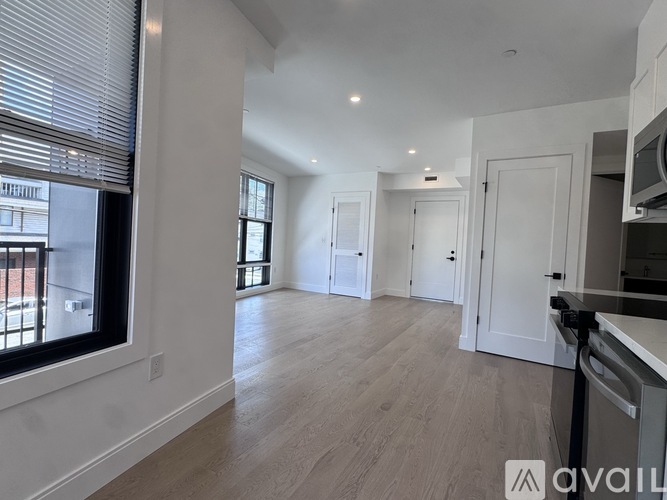 A spacious, empty living room with wooden floors and white walls.