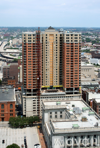 A tall building with a brown and tan facade stands in the middle of a cityscape.