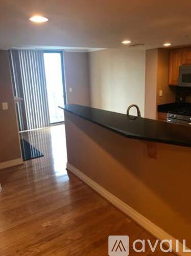 A kitchen with a black countertop and wooden flooring.