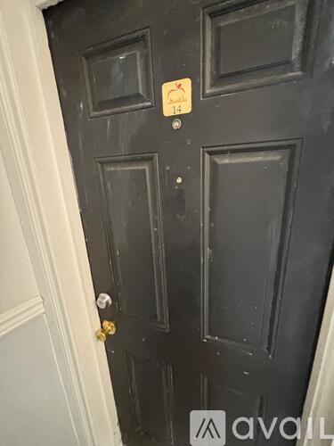 A black door with a gold handle and a yellow sticker on it.