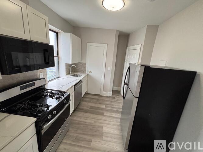 A kitchen with black appliances and white cabinets.