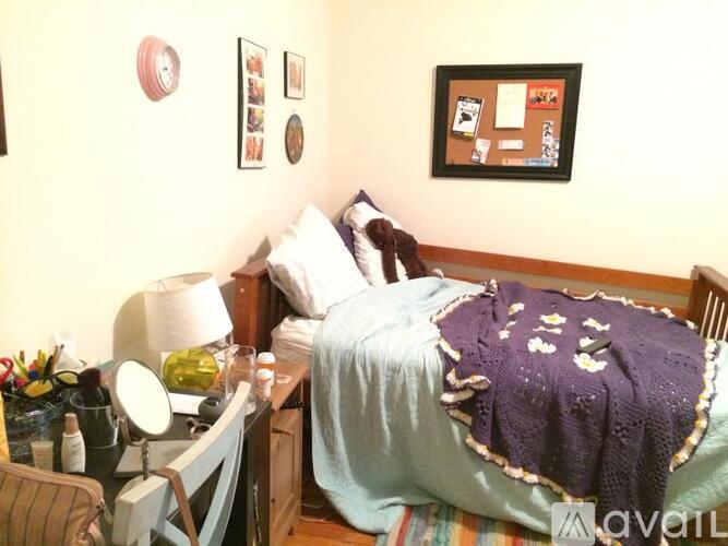 A bedroom with a bed covered in a blue blanket and a purple blanket on top.