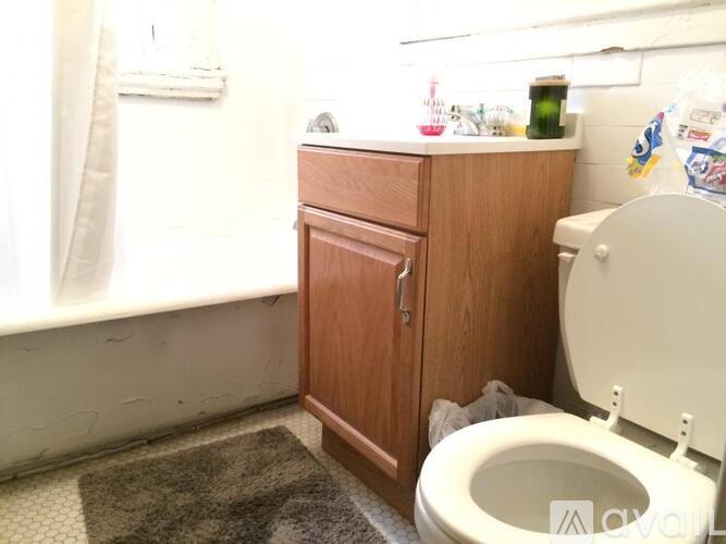 A small bathroom with a toilet and a wooden cabinet.