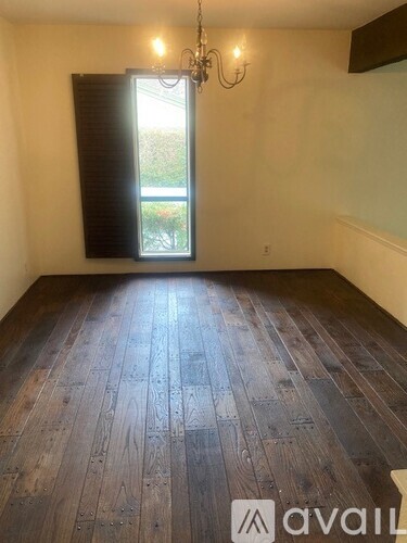 A room with wooden flooring and a window with blinds.