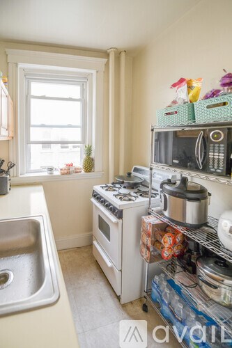 A kitchen with a stove, sink, and window.