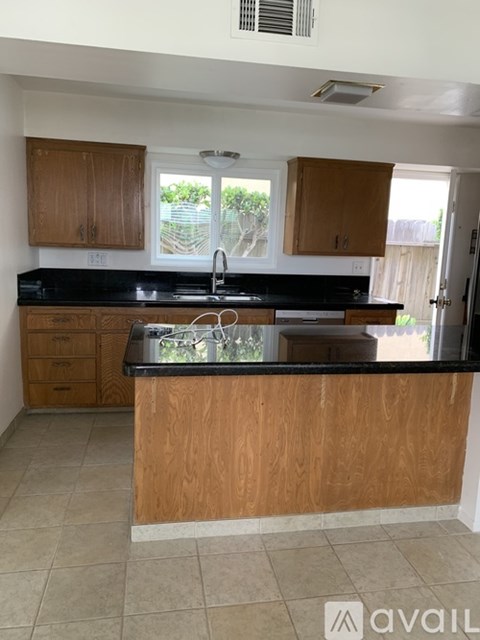 A kitchen with wooden cabinets and black countertops.