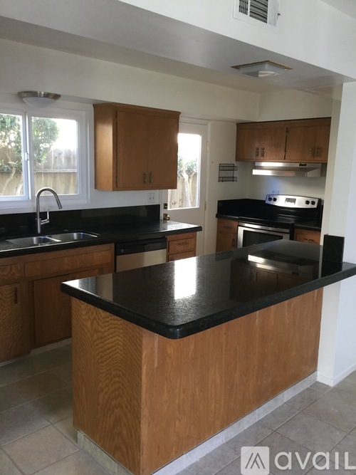 A kitchen with wooden cabinets and black countertops.