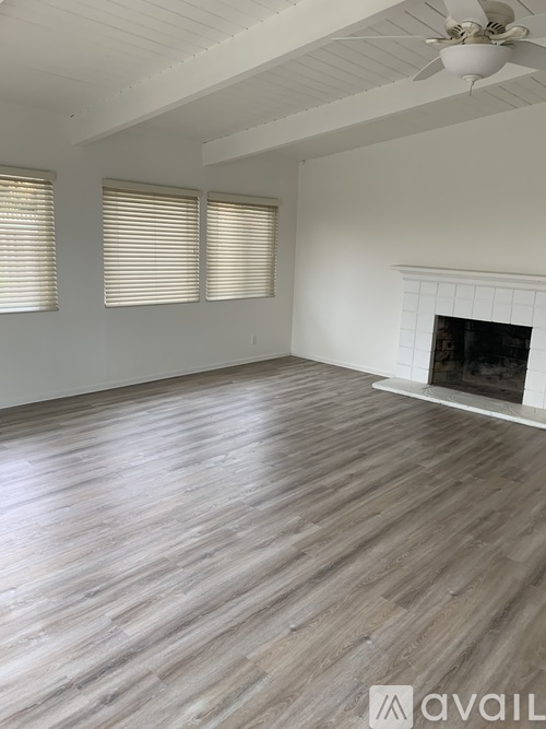 A room with wooden flooring and a fireplace.
