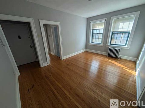 A room with wooden floors and two windows.