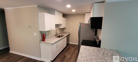 A kitchen with white cabinets and a black fridge.
