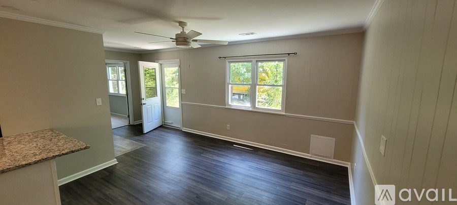 A room with a ceiling fan and a window with a view of trees.