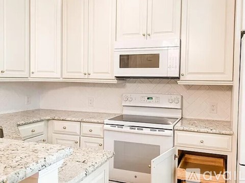A kitchen with white cabinets and granite countertops.