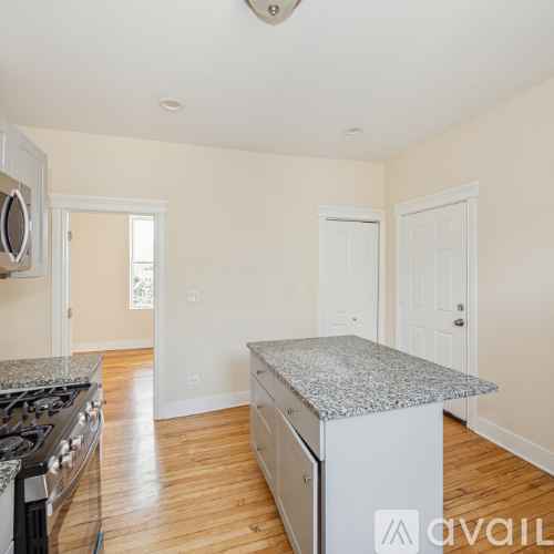 A kitchen with a granite countertop and wooden floors.