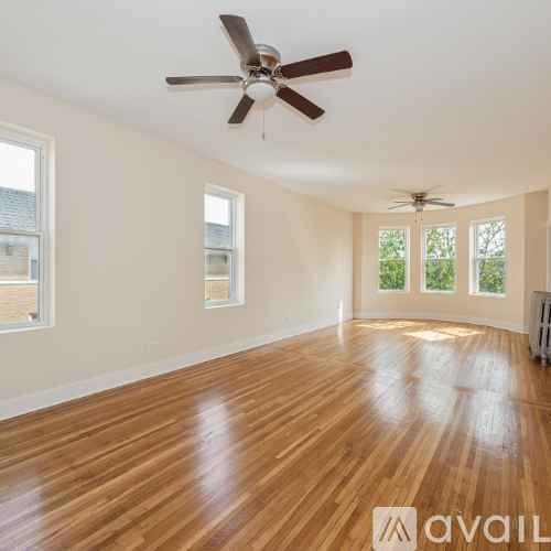 A spacious room with wooden flooring and a ceiling fan.
