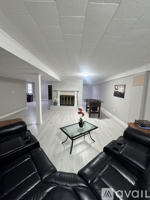A living room with black leather couches and a glass coffee table.