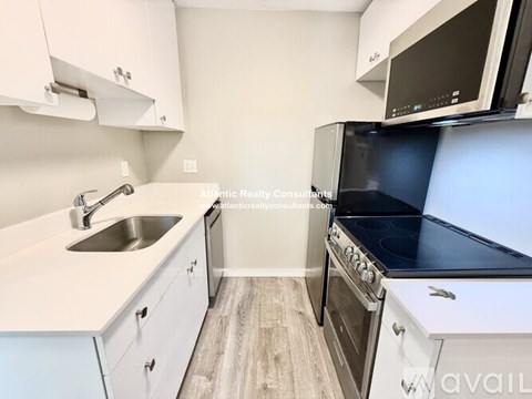 A kitchen with white cabinets and a black stove top oven.