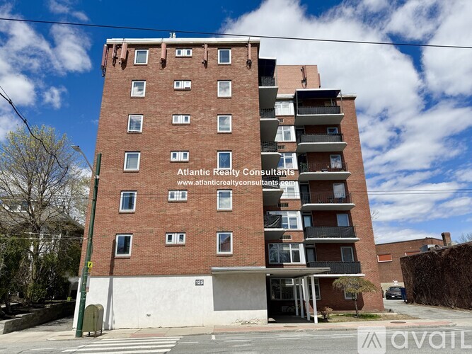 A tall brick building with a balcony on the top floor and a sign for Atlantic Realty Consultants.