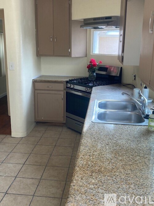 A kitchen with a stove, sink, and cabinets.