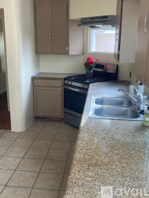 A kitchen with a stove, sink, and cabinets.