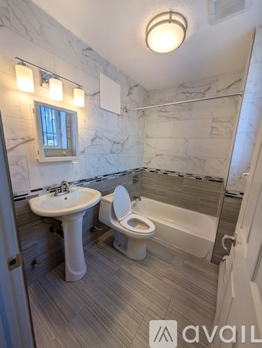 A bathroom with a marble wall and a white toilet.