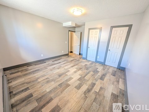 A room with wooden flooring and two doors.