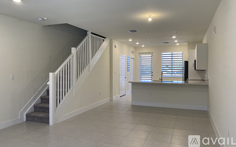A spacious room with a staircase and a window with blinds.