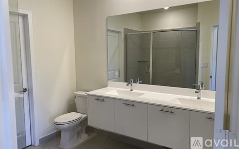 A bathroom with a toilet, sink, and mirror.