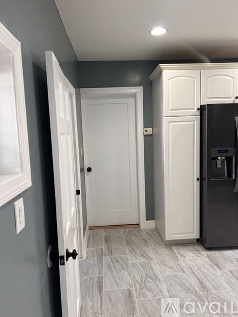 A kitchen with a black fridge and a white door.