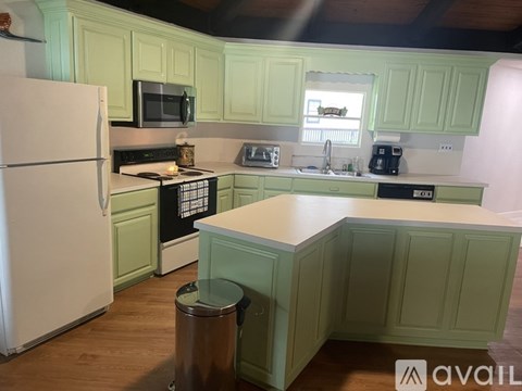 A kitchen with green cabinets and a white refrigerator.