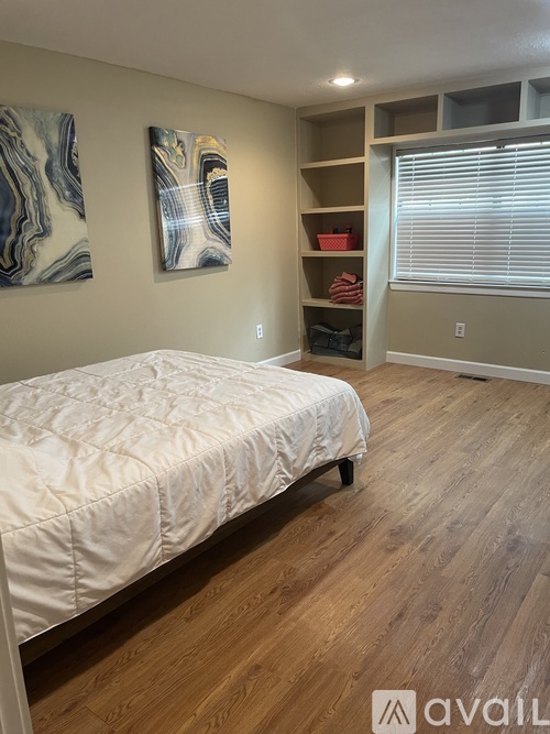 A bedroom with a bed, shelves, and two paintings on the wall.