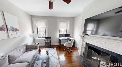 A living room with a grey couch, a fireplace, and a television.