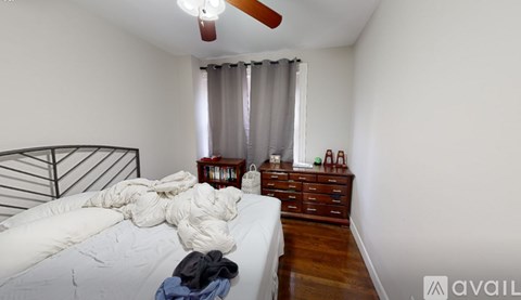 A bedroom with a bed, dresser, and window with curtains.