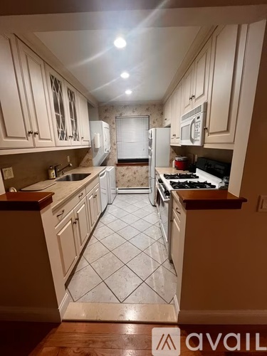 A kitchen with white cabinets and a tiled floor.