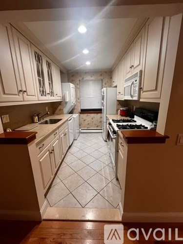 A kitchen with white cabinets and a tiled floor.