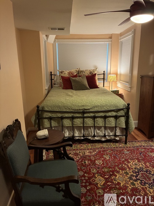 A bedroom with a bed, chair, and rug.