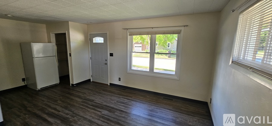 A room with a white fridge and wooden floors.