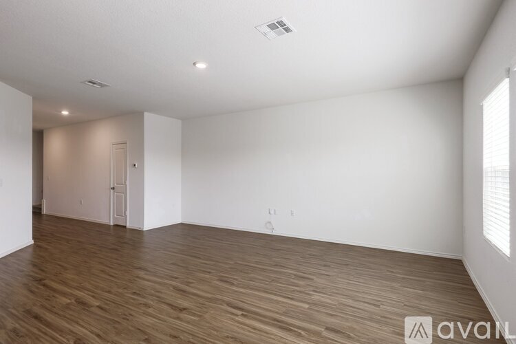 A spacious room with wooden flooring and white walls.