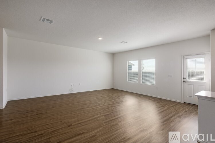 A spacious room with wooden flooring and white walls.