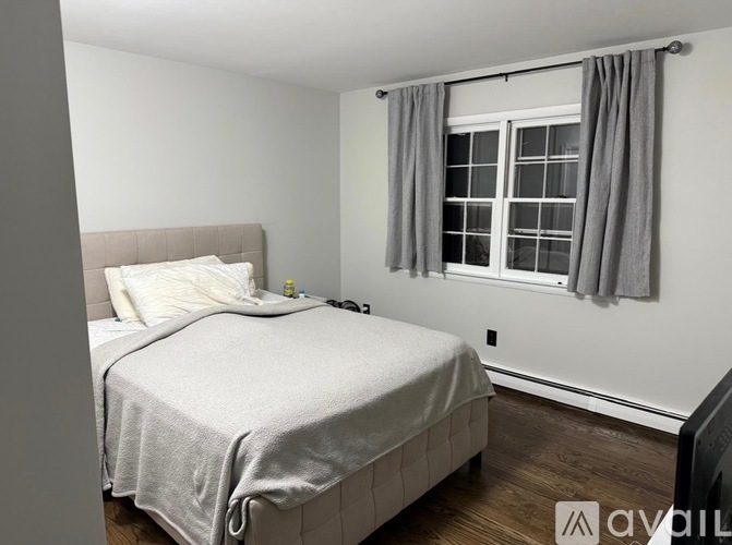 A bedroom with a bed, nightstand, and window.