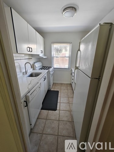 A kitchen with white cabinets and a black mat on the floor.