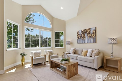 A living room with a large window and a painting on the wall.