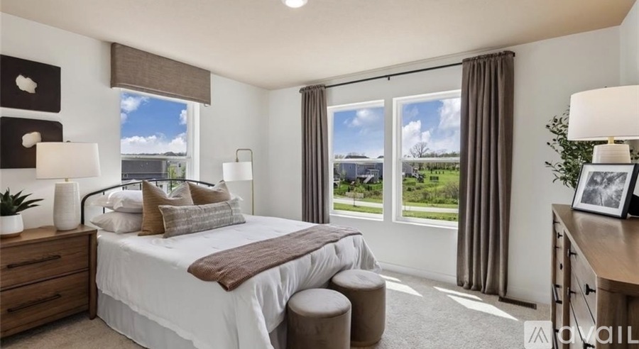 A well-lit bedroom with a large bed, a window with a view of the outside, and a nightstand with a lamp.