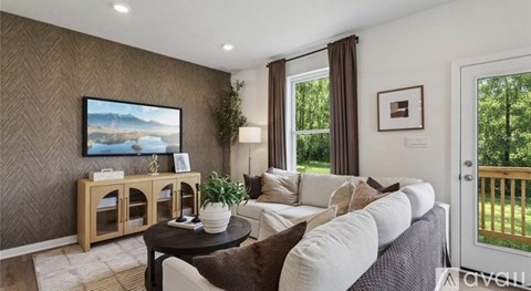 A living room with a grey couch, a wooden cabinet, a painting on the wall, and a potted plant.